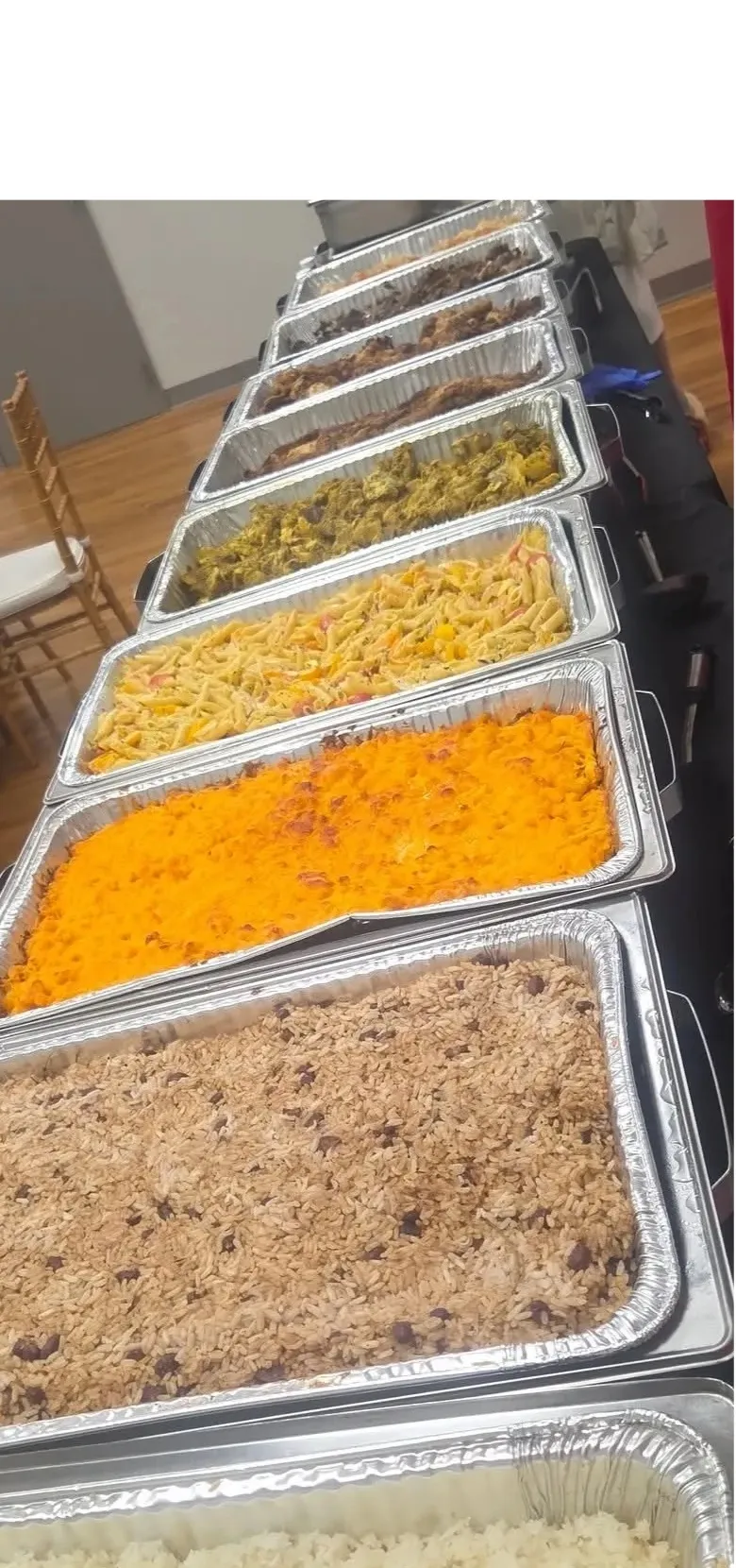 A Los Barbados catering buffet line: rice and peas, macaroni pie, greens and barbecued meats